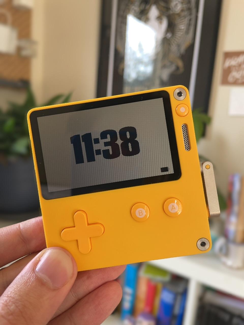 A small yellow handheld console with a crank