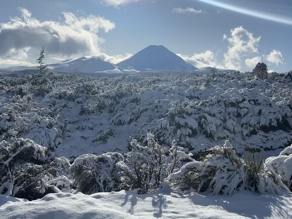 A snowy landscape with the silhouette of Mount Ruapehu on the horizon