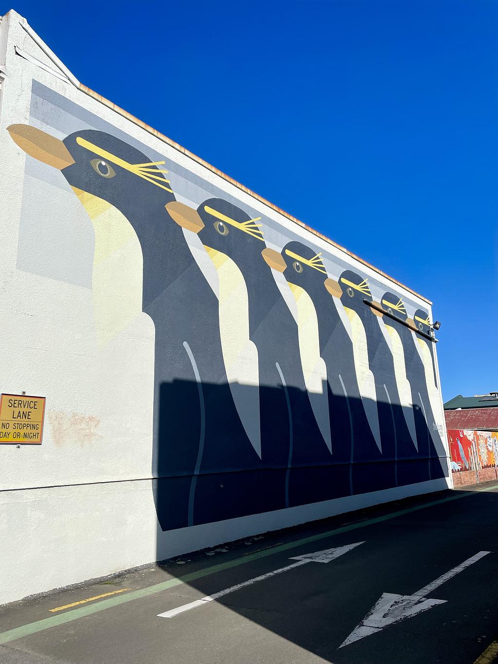 A line of 6 penguins graffitied on a wall